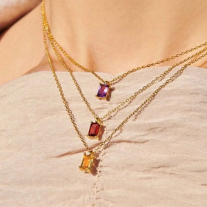 Prism cut gemstone necklaces in purple, red, and yellow on 18K gold chains.