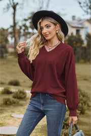 Burgundy textured cable knit V-neck sweater with long sleeves.