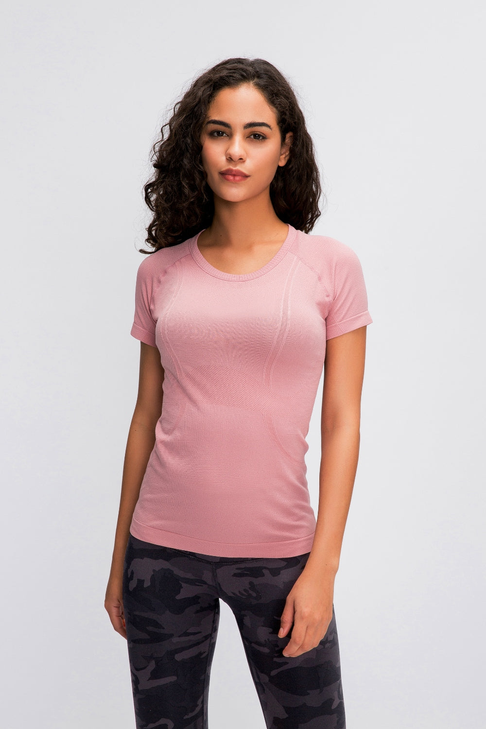 Blush pink activewear tee with seamless knit and subtle contouring details.
