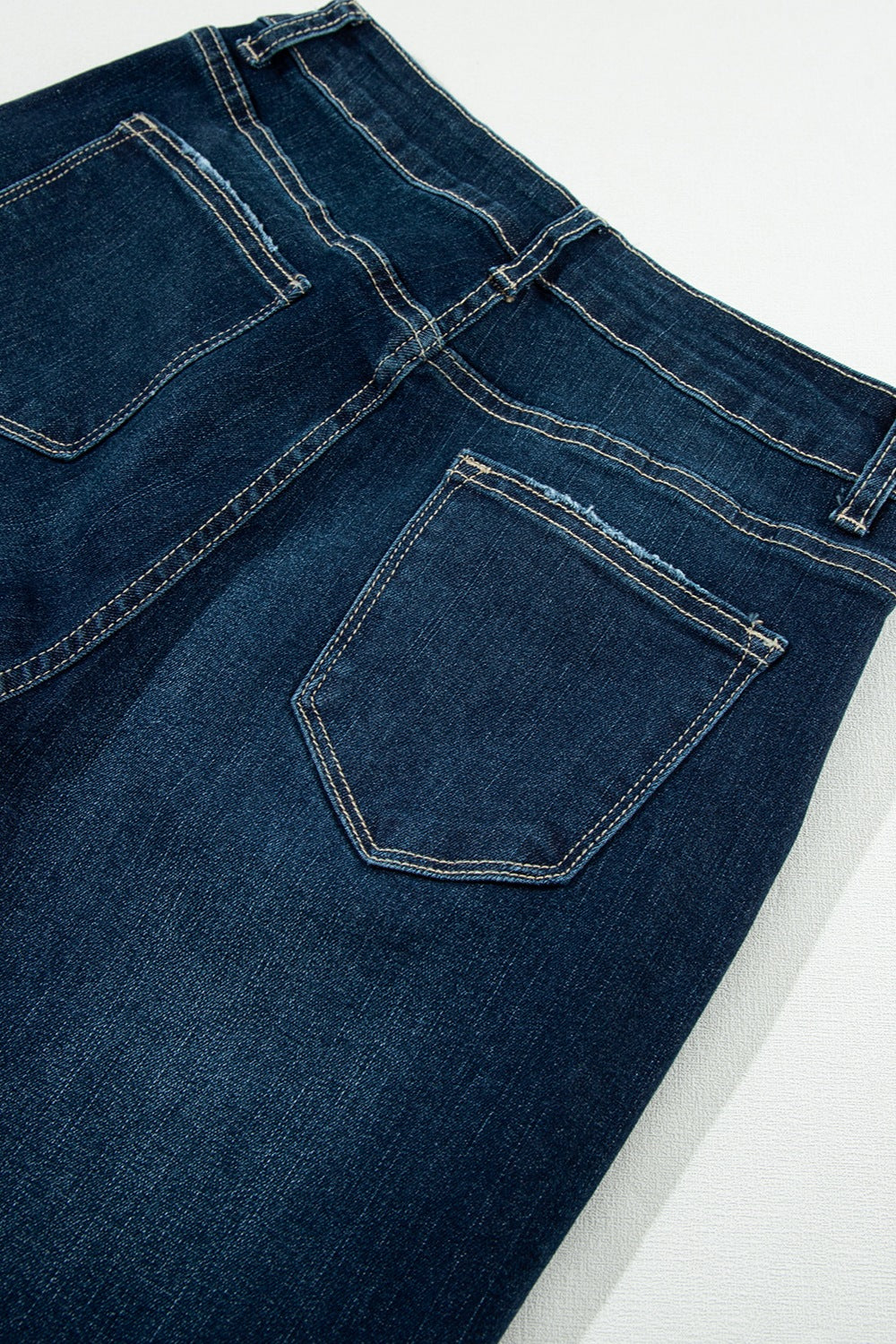 Dark wash denim wide leg jeans with rough frayed edges and contrast stitching.