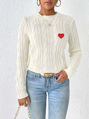 White cable knit sweater with embroidered red heart detail, crew neck, long sleeves.