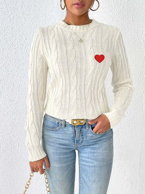 White cable knit sweater with embroidered red heart detail, crew neck, long sleeves.
