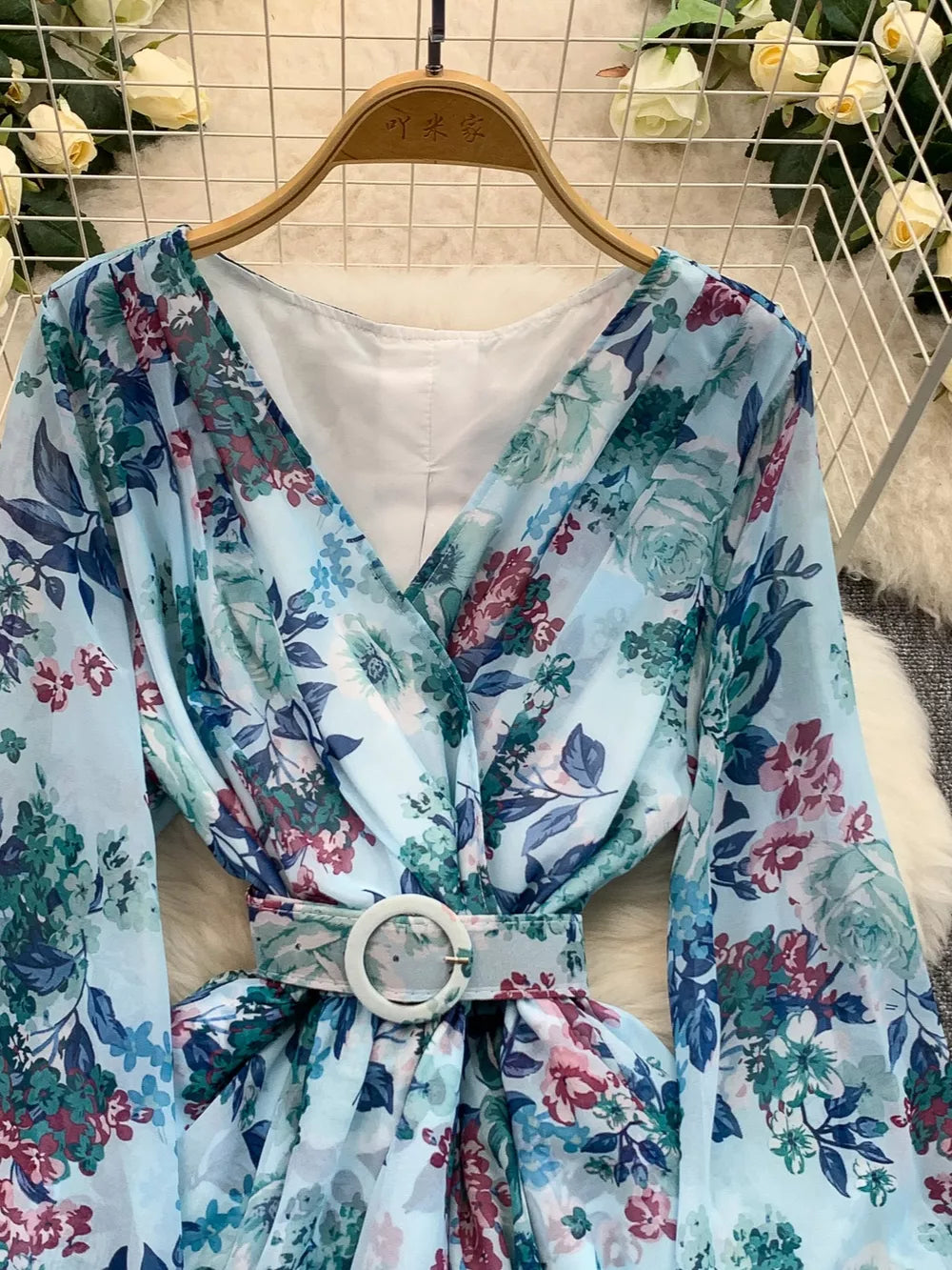 Light blue floral wrap mini dress with V-neck, long sleeves, and white buckle belt.