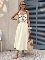 A-line midi dress in beige with black trim and a large bow detail on the bust.