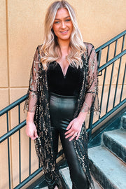 Black sequin duster with flared sleeves over a velvet bodysuit and faux leather pants.
