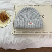 Light gray chunky knit beanie with ribbed texture and a small white label.