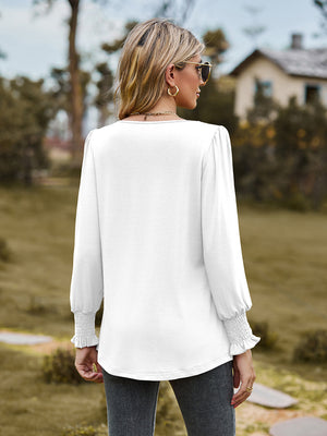 White long sleeve blouse with gathered yoke and smocked cuffs.