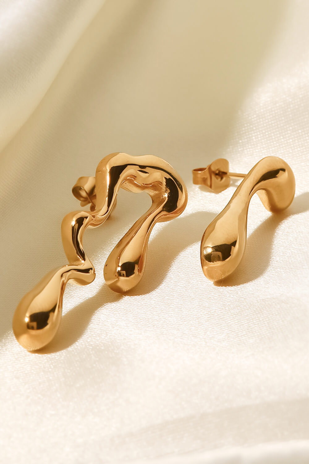 Gold asymmetrical drip earrings with a fluid, artistic design.