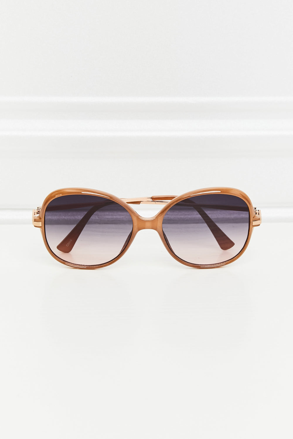 Oversized round frame sunglasses in caramel with gradient lenses and gold accents.