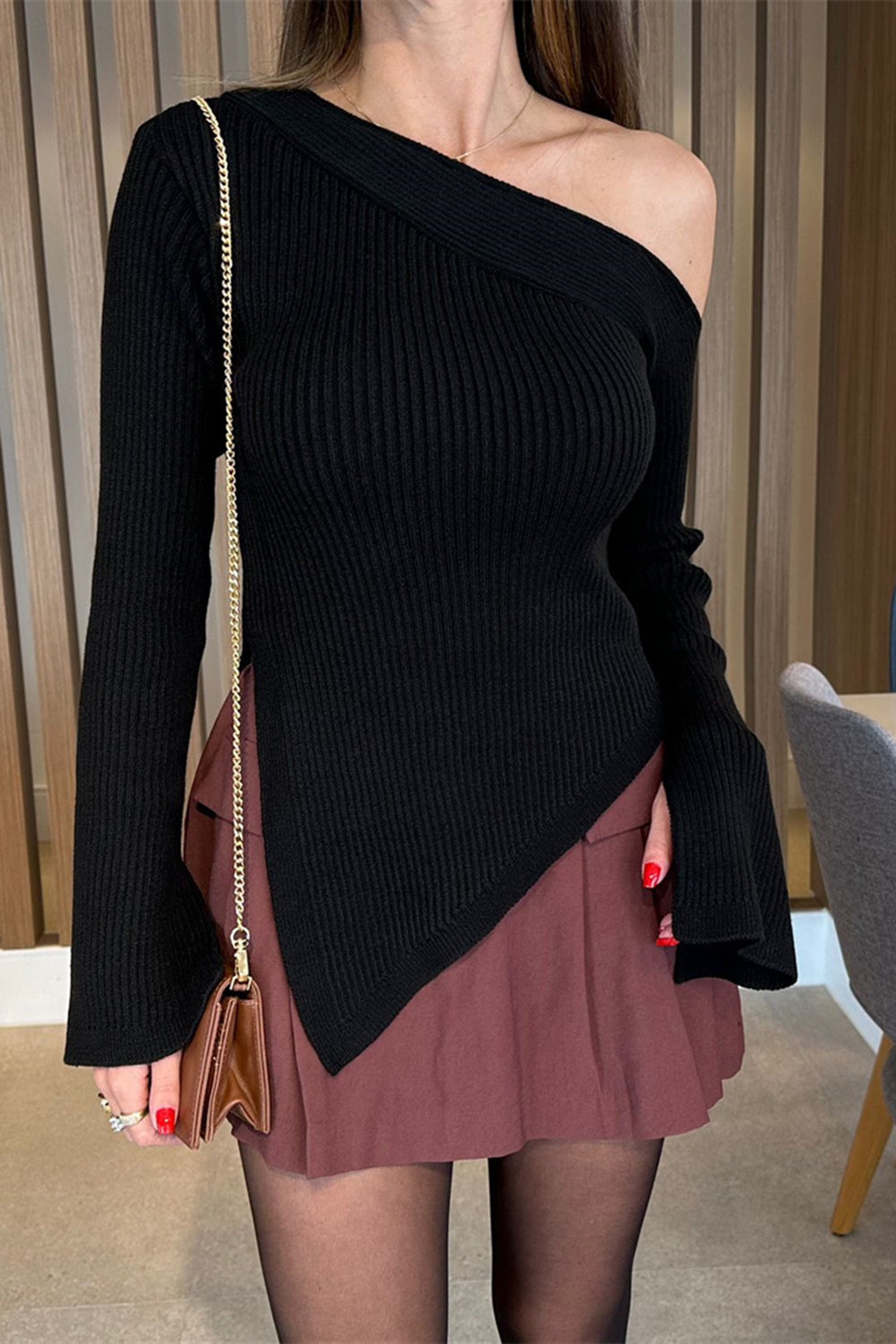Black asymmetric ribbed knit sweater with flared sleeves and off-the-shoulder neckline.