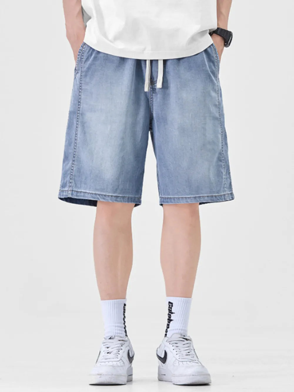 Light blue denim shorts for men with drawstring waist and loose fit.