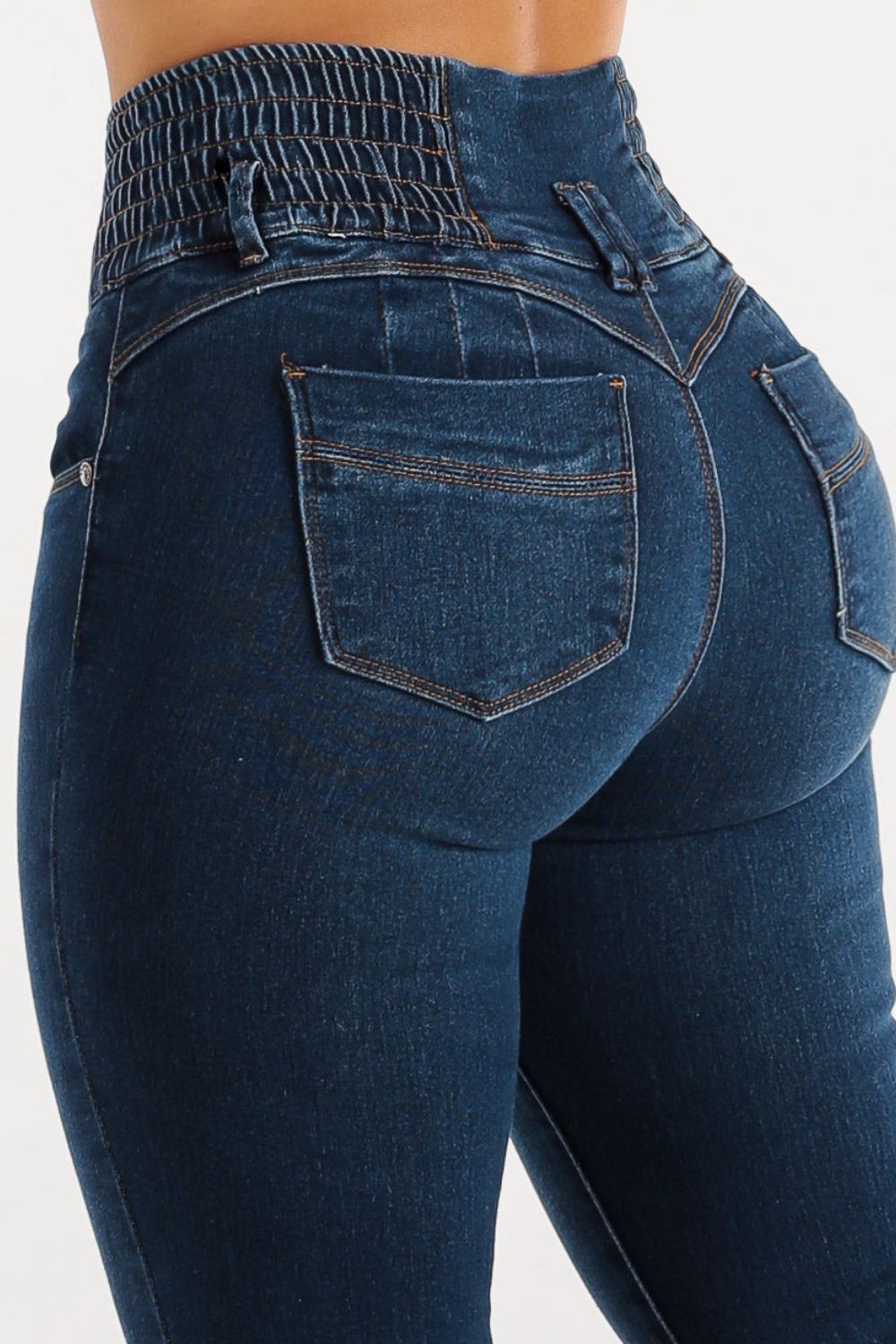 Dark wash skinny jeans with a sculpted, smocked waistband and button fly.