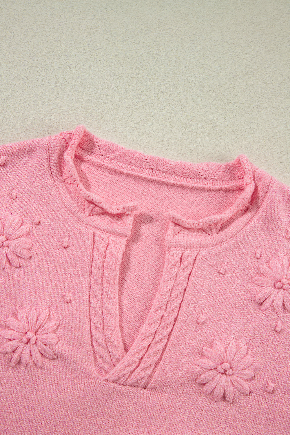 Blush pink knit sweater with embroidered floral details and notch neck.