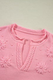 Blush pink knit sweater with embroidered floral details and notch neck.