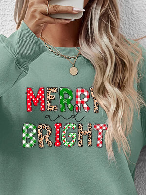 Sage green sweatshirt with "Merry and Bright" graphic in festive patterns.