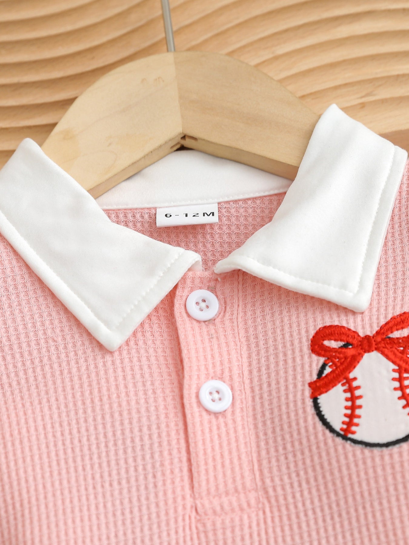Pink baby dress with white collar, buttons, and embroidered baseball detail.