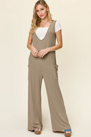 Mocha wide-leg jumpsuit with deep V-neck, pockets, and a white tee.