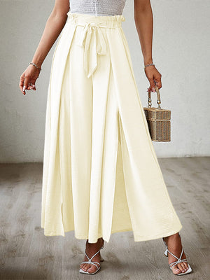Pastel yellow pleated palazzo pants with sash and thigh-high slits