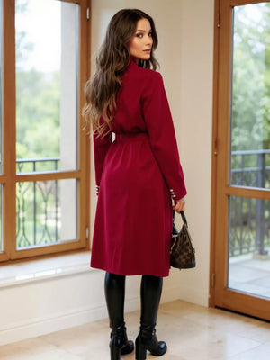 Red tailored double-breasted trench coat with waist tie and button details.
