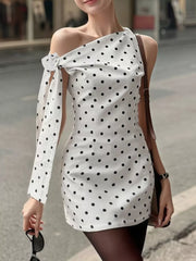 White polka dot mini dress with asymmetrical neckline and bow detail on sleeve.