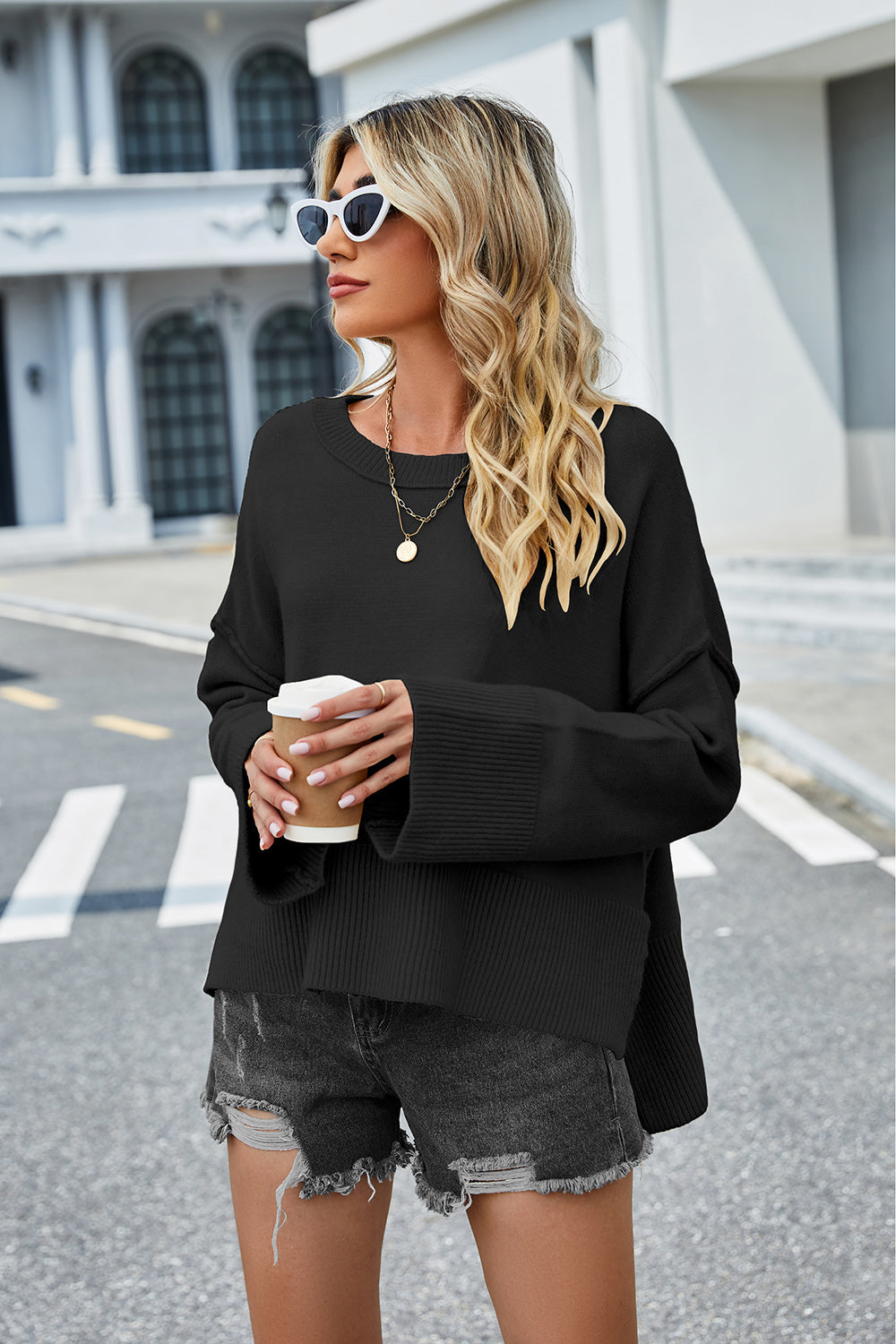 Black acrylic knit sweater with flared sleeves and slit hem detail.