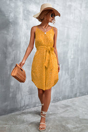 Mustard daisy print slip dress with tie waist, V-neck, and spaghetti straps.