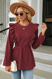 Burgundy textured peplum blouse with ruffle details and long sleeves.