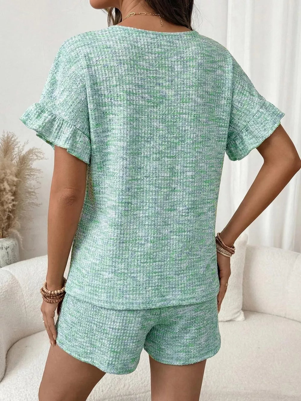 Green ruffled sleeve two-piece set with textured fabric and drawstring shorts.