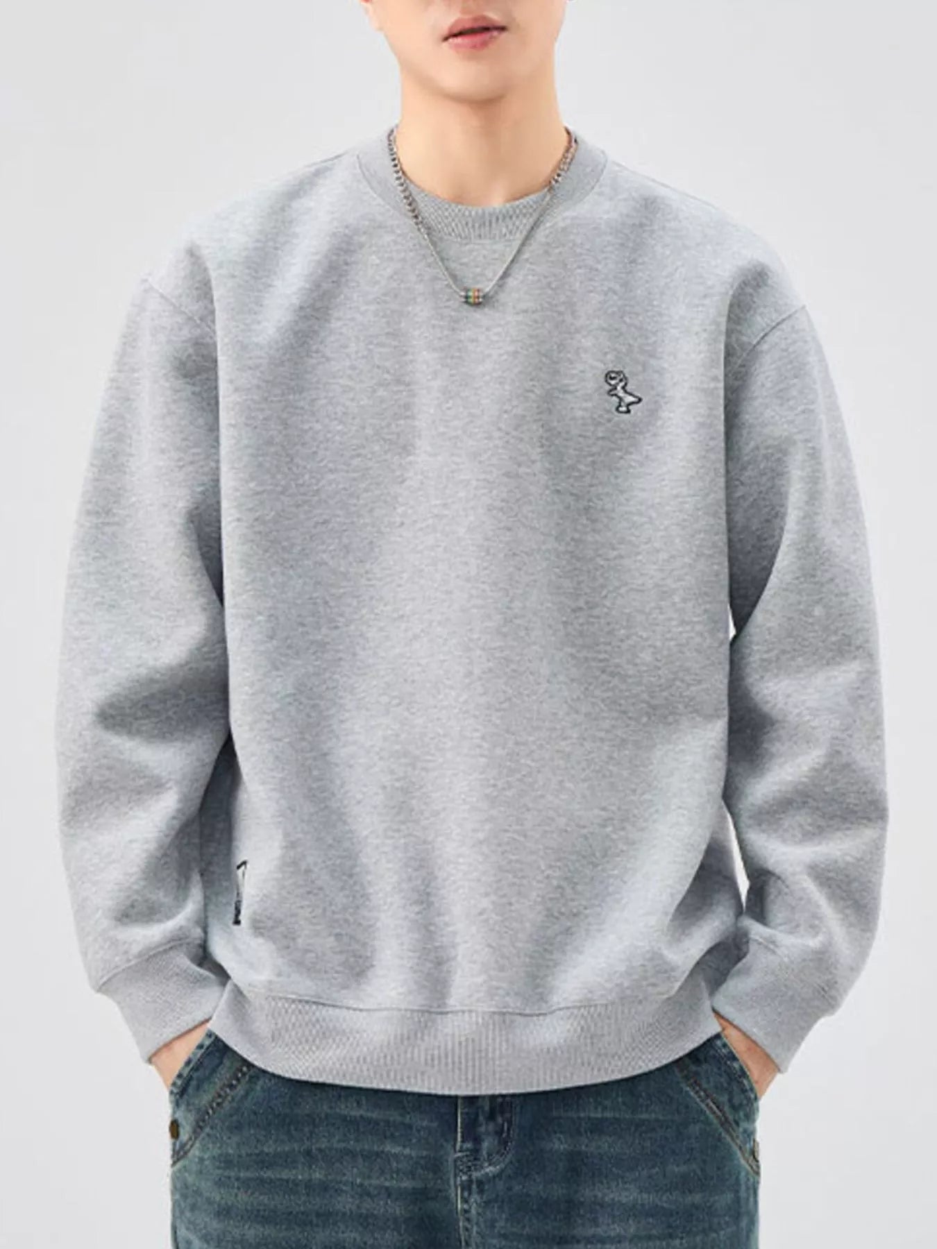 Gray sweatshirt with crew neck, long sleeves, and embroidered dinosaur detail.