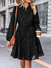 Black textured puff sleeve tiered mini dress with button front and tie waist.