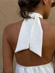 White halter cami with textured fabric and backless tie detail.