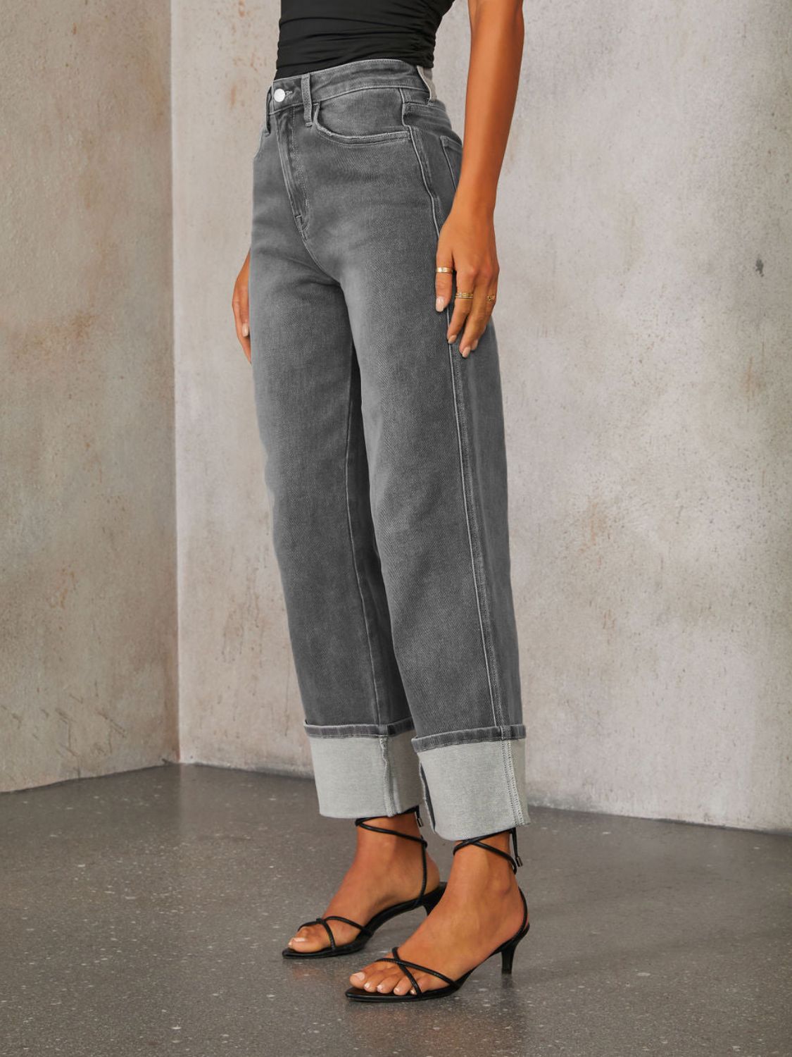 Dark wash denim jeans with wide legs and a cuffed hemline.