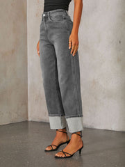 Dark wash denim jeans with wide legs and a cuffed hemline.