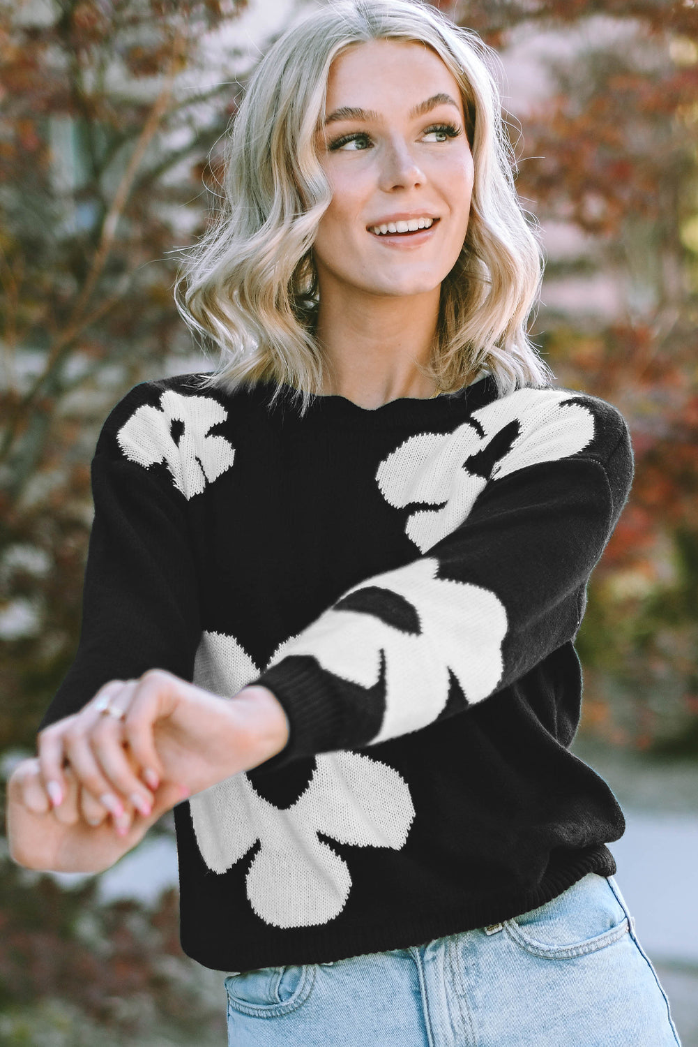 Black acrylic sweater with white floral intarsia pattern and scalloped neckline.