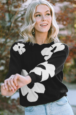Black acrylic sweater with white floral intarsia pattern and scalloped neckline.