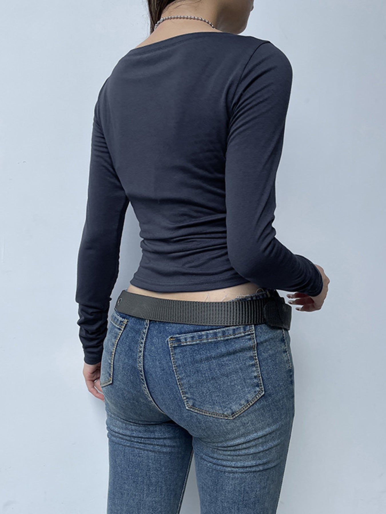 Dark blue long sleeve t-shirt with buttoned neckline and ruched sides, paired with jeans.