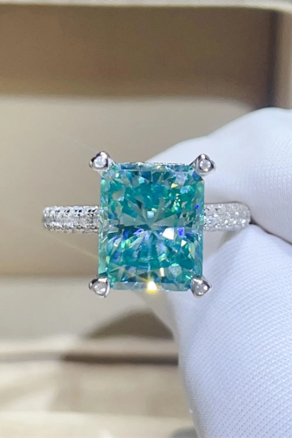 Radiant cut teal pave ring with diamond band and four prong setting.