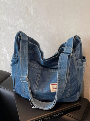 Slouchy blue denim crossbody bag with contrast stitching and adjustable strap.