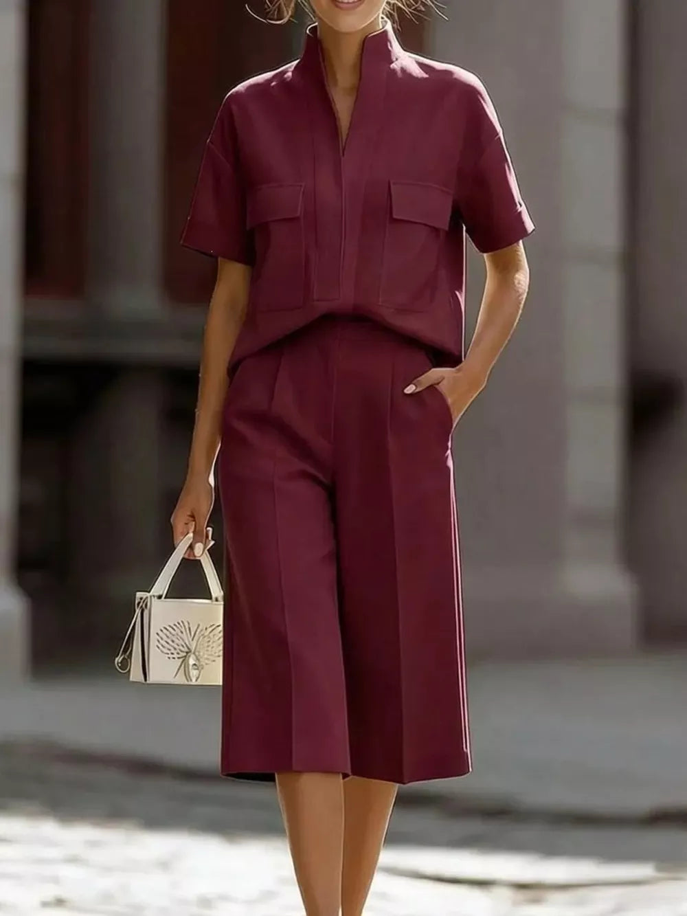 Burgundy two-piece set with pocketed top and wide-leg pants, styled with a white handbag.