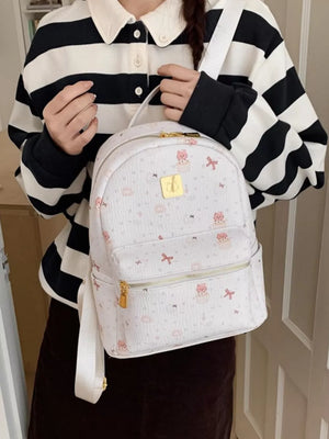Charming mini backpack in ivory with playful cat and cupcake motifs, gold hardware.