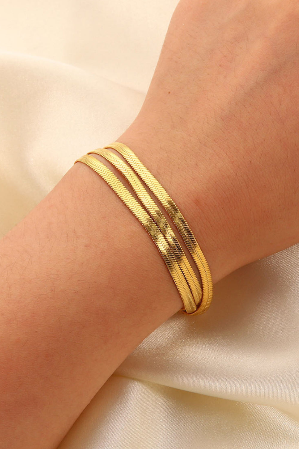 Triple gold herringbone chain bracelet crafted with a flat, flexible design.