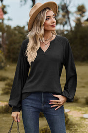 Black waffle knit raglan sweater with laser cut sleeves and v-neck