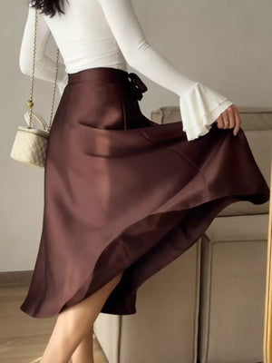 Burgundy satin midi skirt with a tie waist and bow detail.