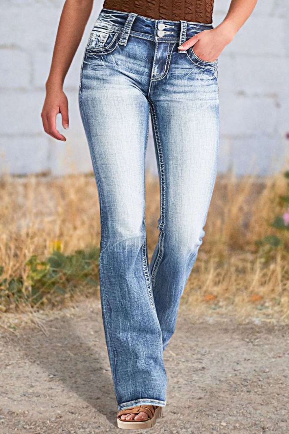 Light wash bootcut jeans with embroidered star detail on back pockets and white stitching.