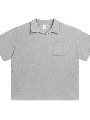 Boxy knit polo shirt in gray with a patch pocket and open collar.