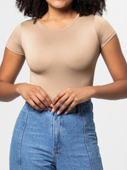 Tan scoop-neck bodysuit with short sleeves, smooth fabric, worn with jeans.