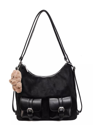 Black suede half-moon bag with two front buckle pockets and a fluffy charm.