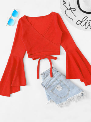 Red wrap crop top with bell sleeves and tie waist, styled with denim shorts.