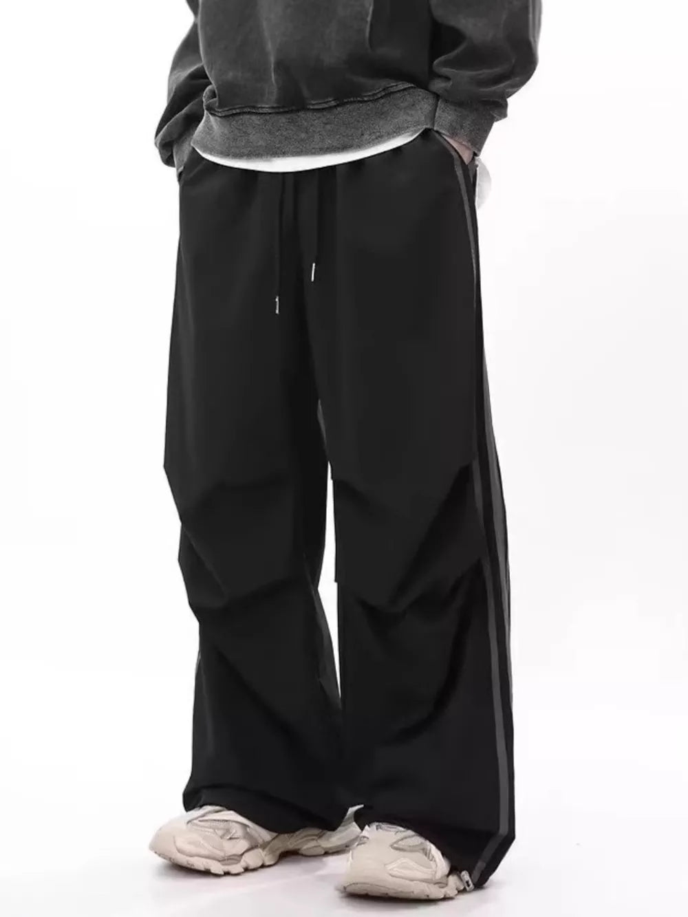 Men's black wide-leg sweatpants with drawstring and side stripe detail.