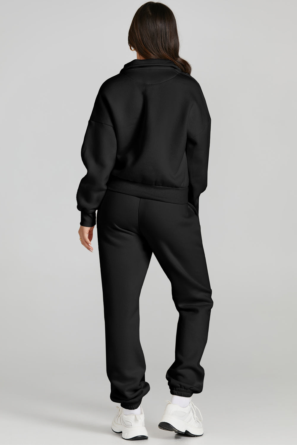 Black quarter-zip sweatshirt and jogger set with cuffed ankles and white sneakers.